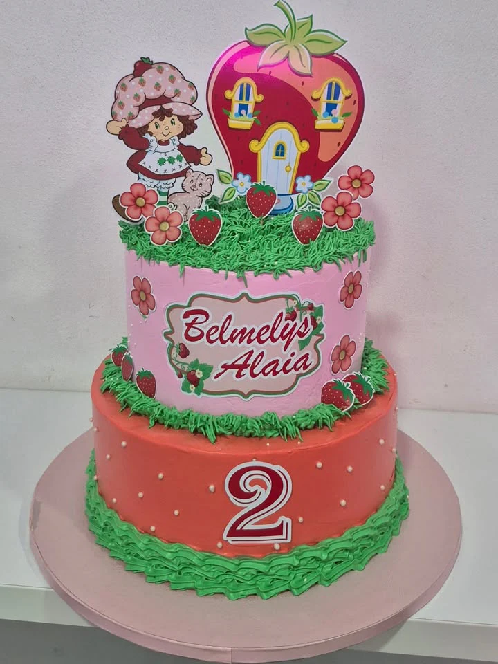 Tarta rosa y coral de dos pisos con fresas, flores y decoración infantil