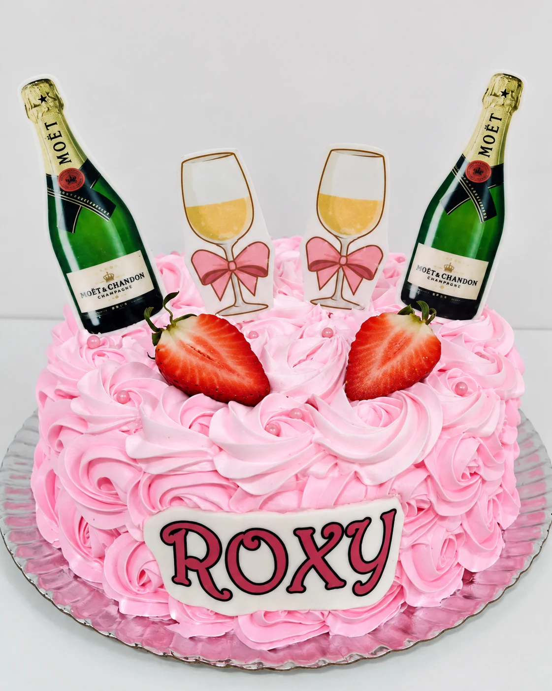 Tarta rosa con rosetones de crema, fresas y detalles de botellas y copas